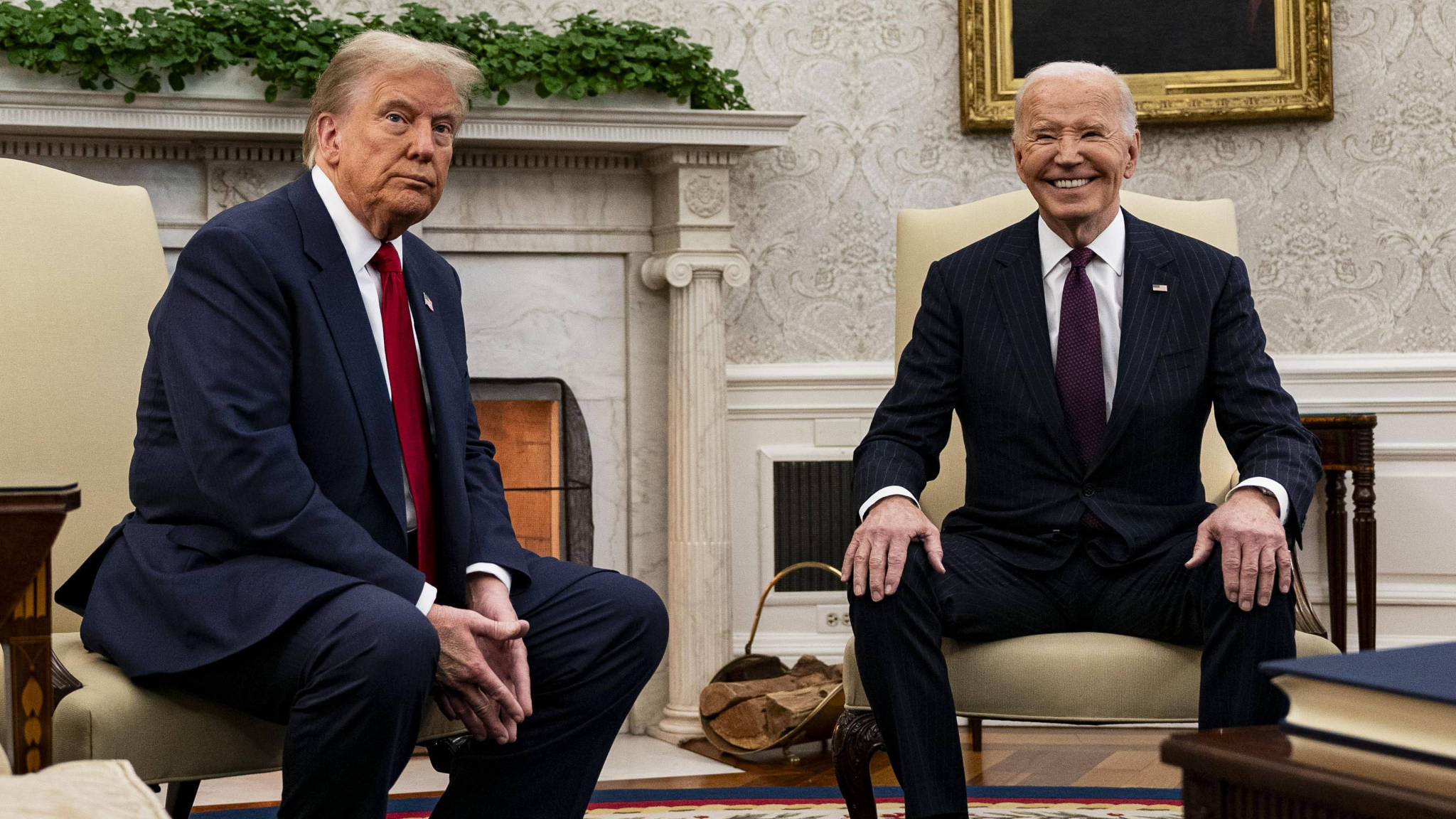Donald Trump and Joe Biden sitting next to one another in the Oval Office, Trump with a frown on his face, Biden with a huge grin on his face