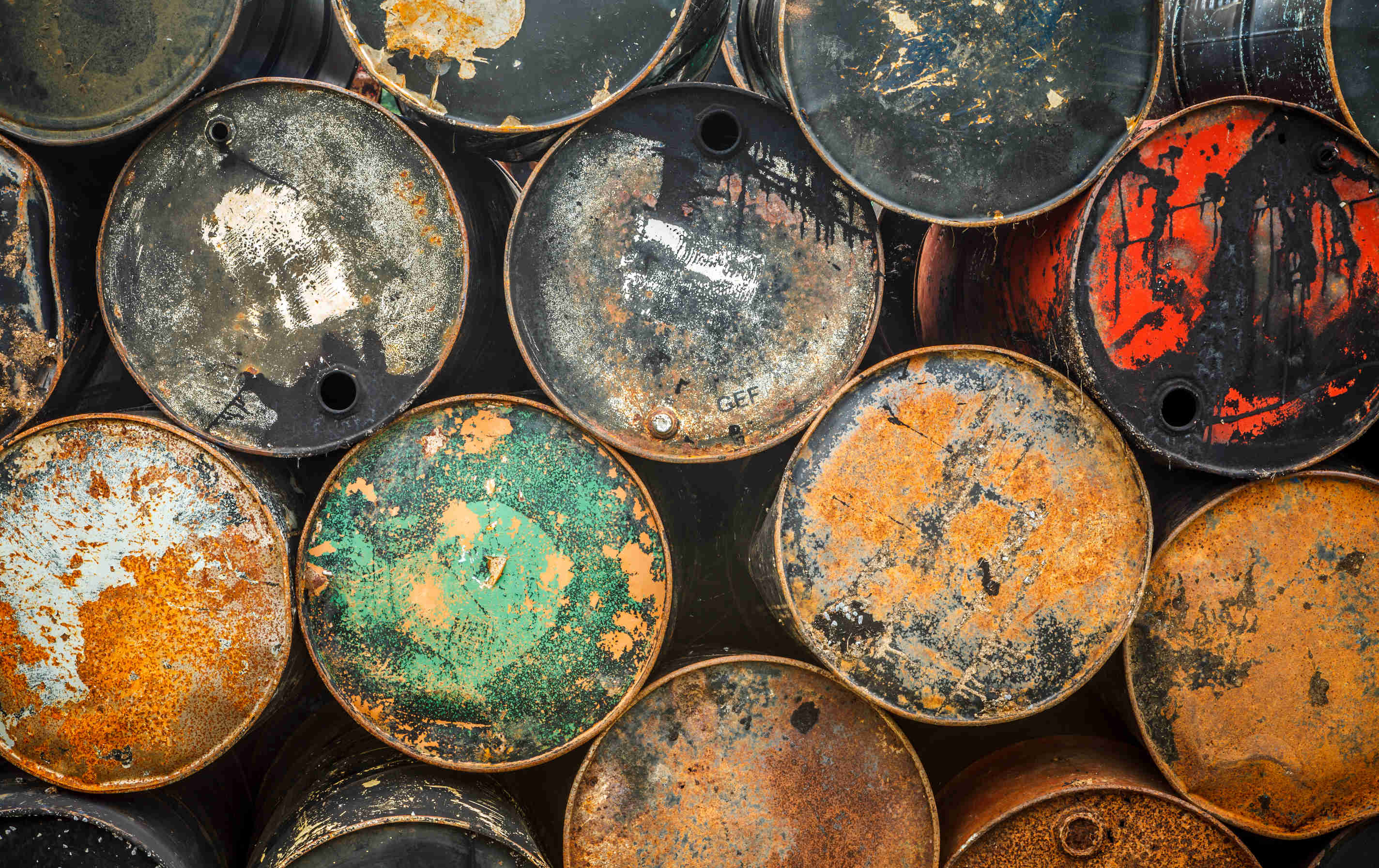 A side view of a bunch of colourful oil barrels piled upon one another