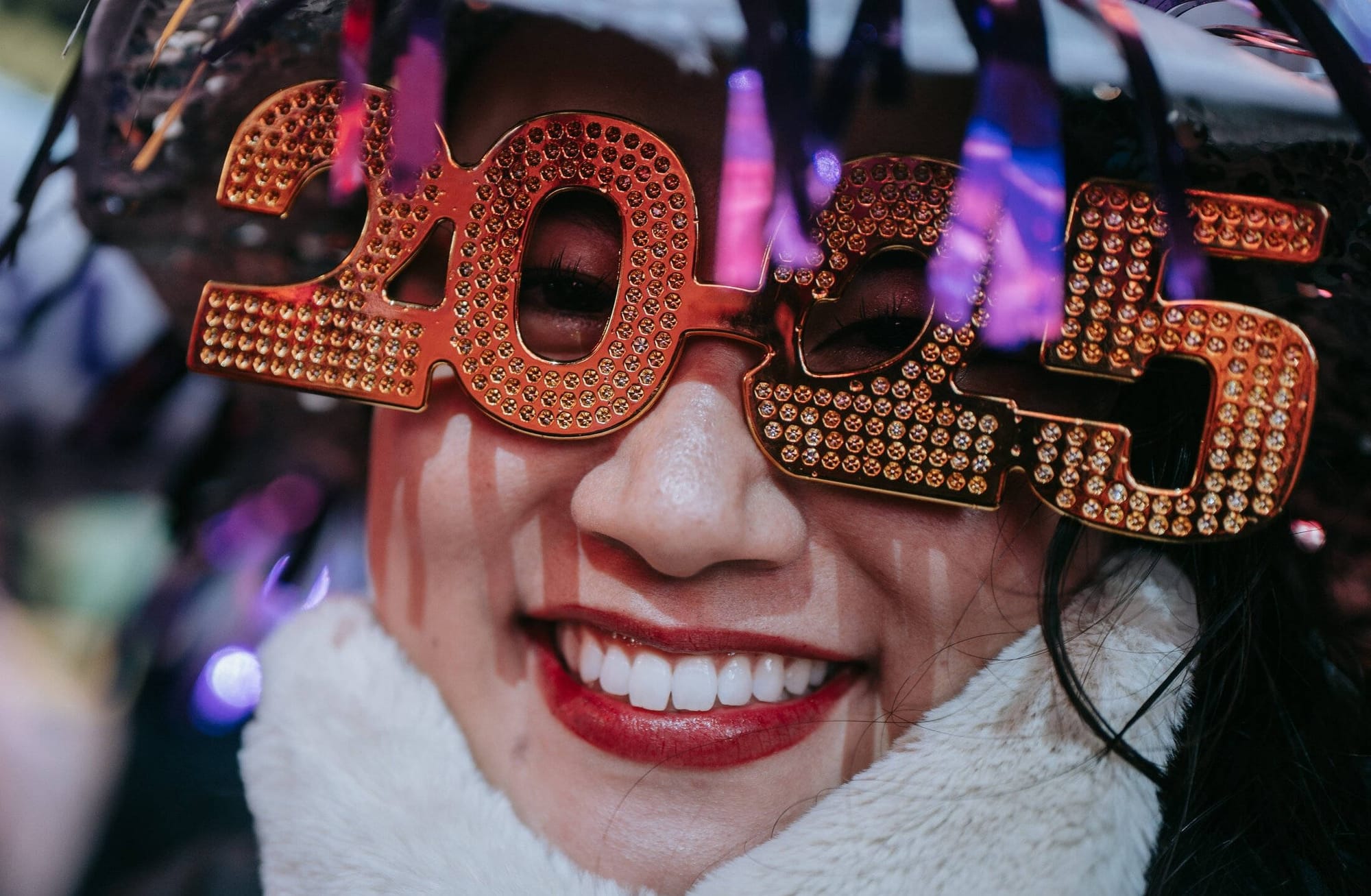 A smiling woman wearing 2025 New Year's Eve glasses