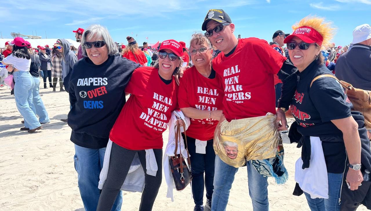 A group of people wearing "Real Men Wear Diapers" and "Diapers over Dems" t-shirts and sweaters