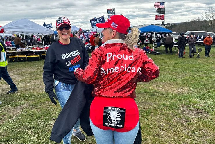 A woman sticking out her rear end, while showing off her "Real Men Wear Diapers" worn over her pants