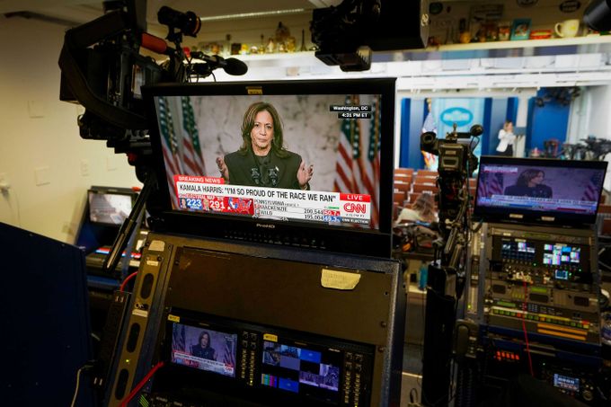 Kamala Harris depicted on video screens giving her concession speech, in the White House Press Briefing Room