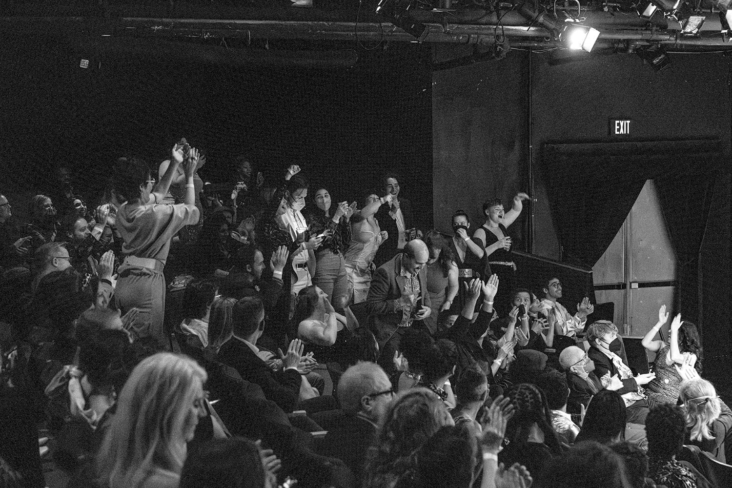 A black and white photo of an audience clapping and cheering.