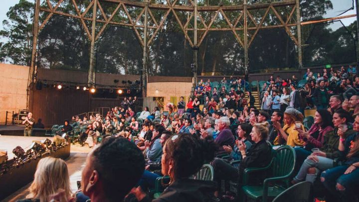 An audience sits outside watching a production at Cal Shakes.