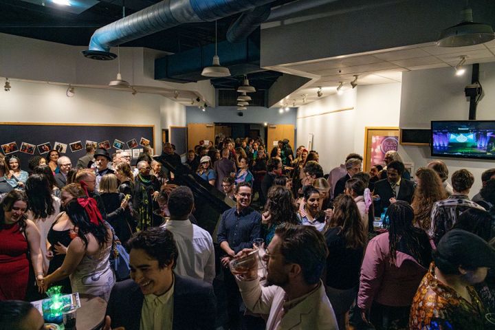 A large group of people standing in a reception hall talking and drinking.