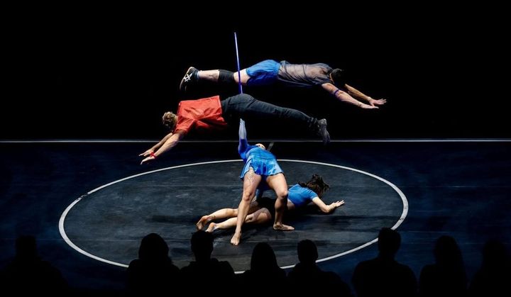 Acrobats on stage leap on stage doing flips.