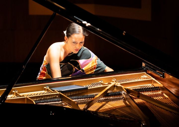 Mahani Teave plays the piano, the camera shows her from the back of the piano.