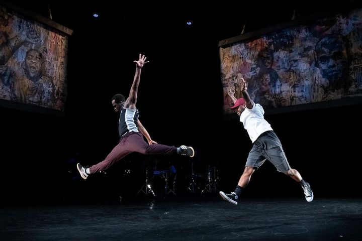 Two dancers leap with their arms outstretched.