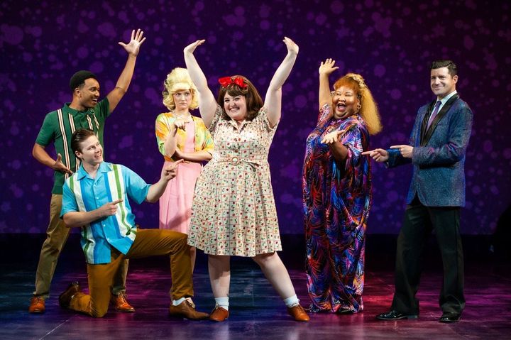A group of young people dance wearing 1960s clothing.