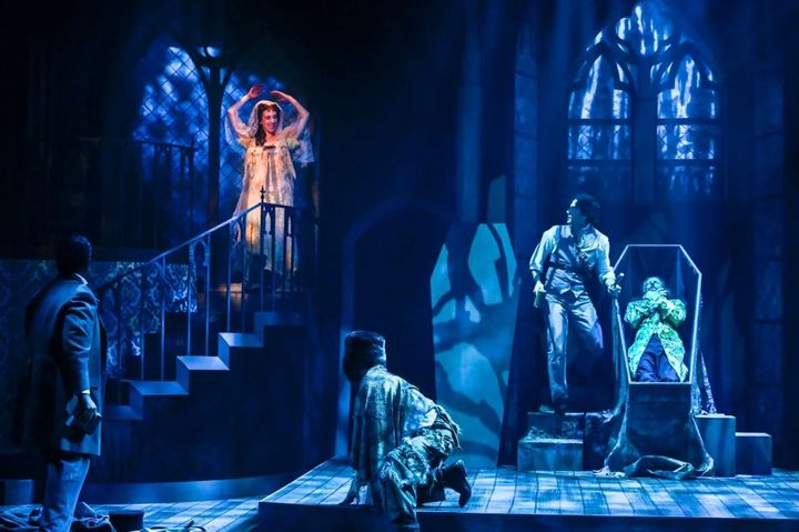 A bride of Dracula comes down the stairs as Jonathan Harker opens Dracula's casket.