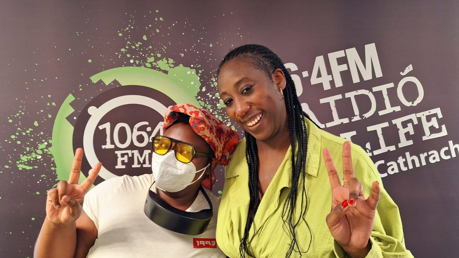 Two west african people at a radio station showing the peace sign.
