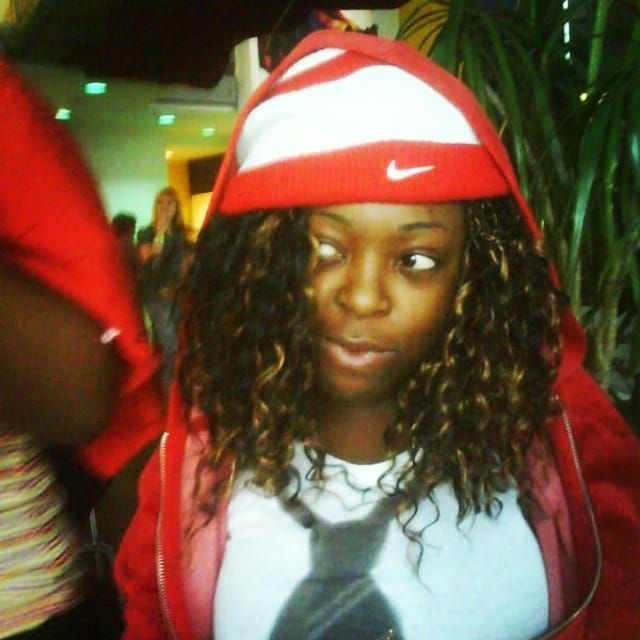 A young west African person look to the mischievously  left, wearing red and white