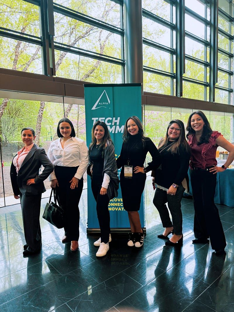 Group of Latina tech leaders standing in front of a banner