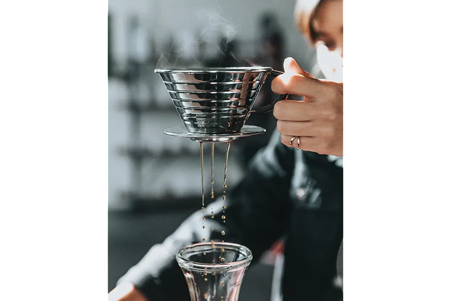 Person holding a drip coffee maker over carafe