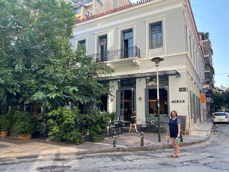 Street scene with green tress and a building in the background, Karina standing in the foreground