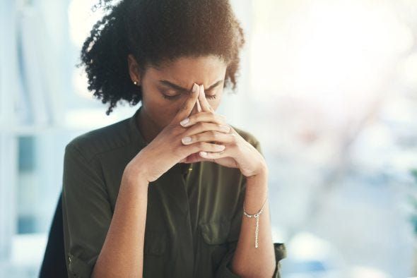 Black woman resting her head on her hands with fingers pointed together.