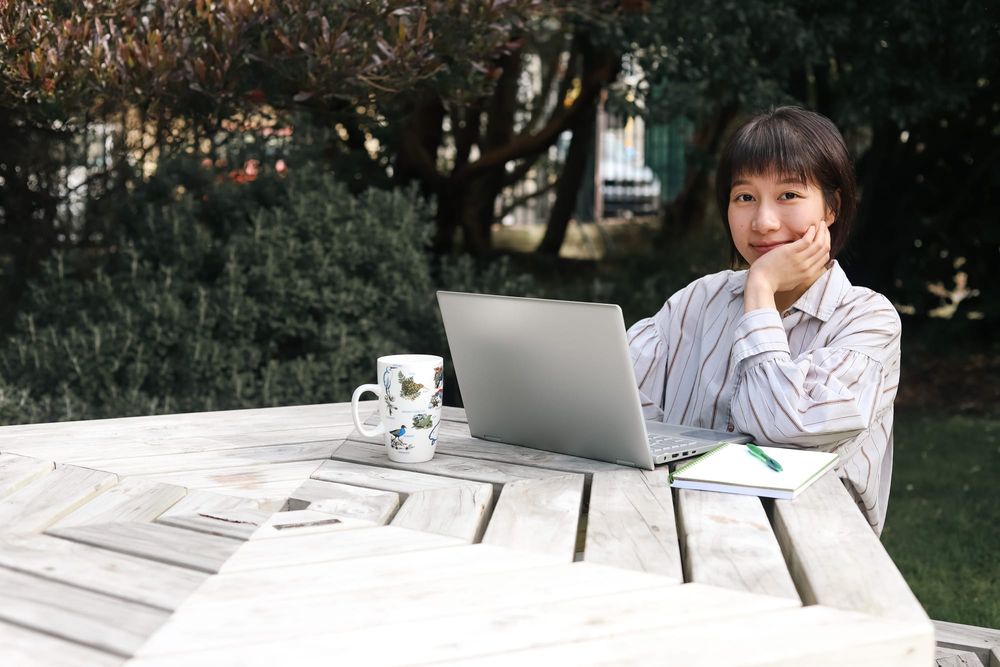 Woman working outdoors with laptop and coffee mug post image