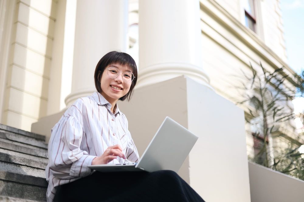 Smiling woman using laptop outdoors post image
