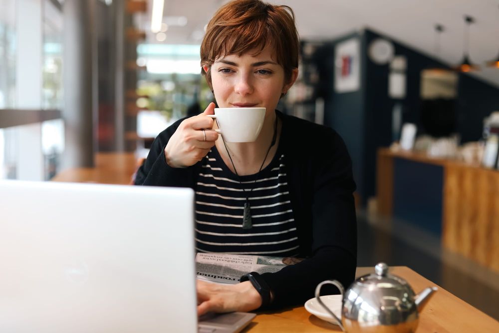 Woman holding cup while working in cafe post image