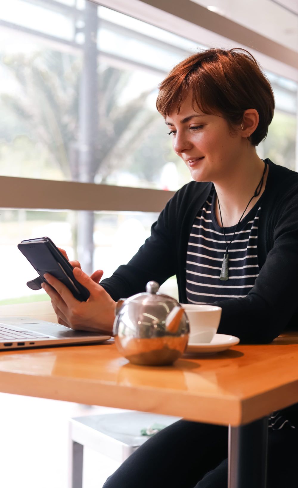 Woman smiling at phone in cafe post image