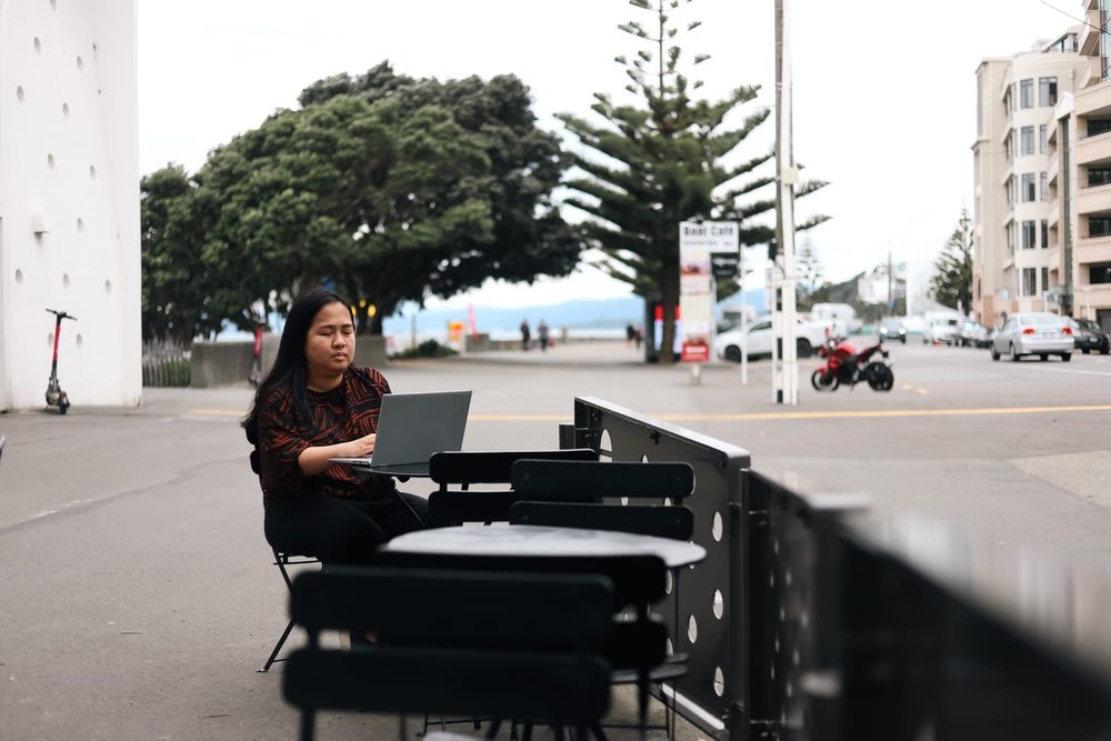 Woman working on laptop at outdoor café tables post image