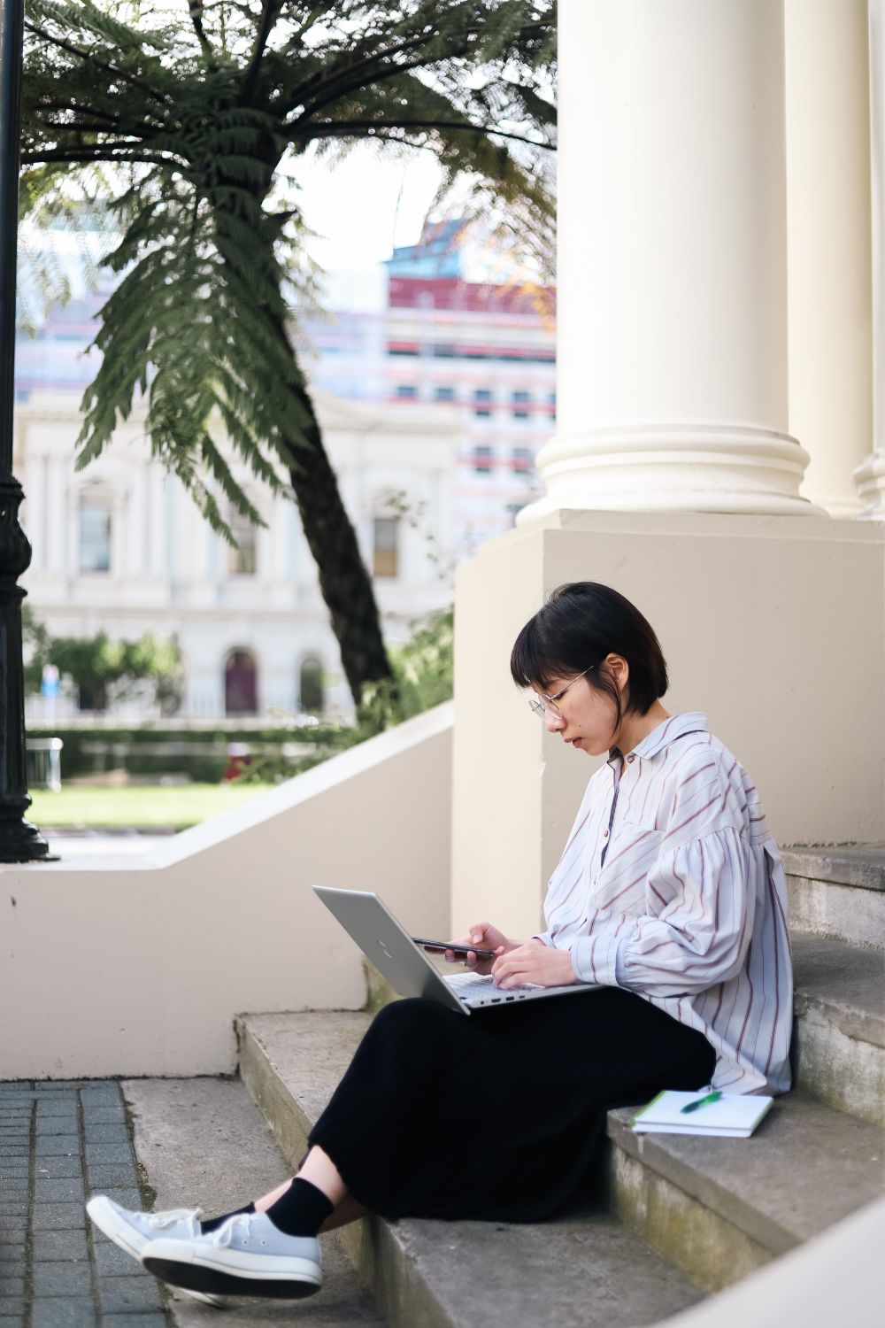Woman working on laptop outdoors post image
