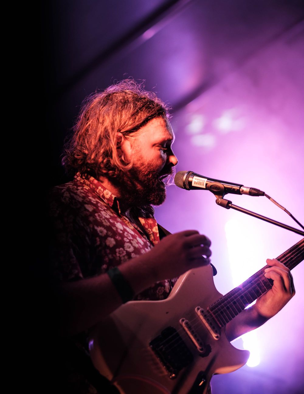 Musician in floral shirt under stage lights post image