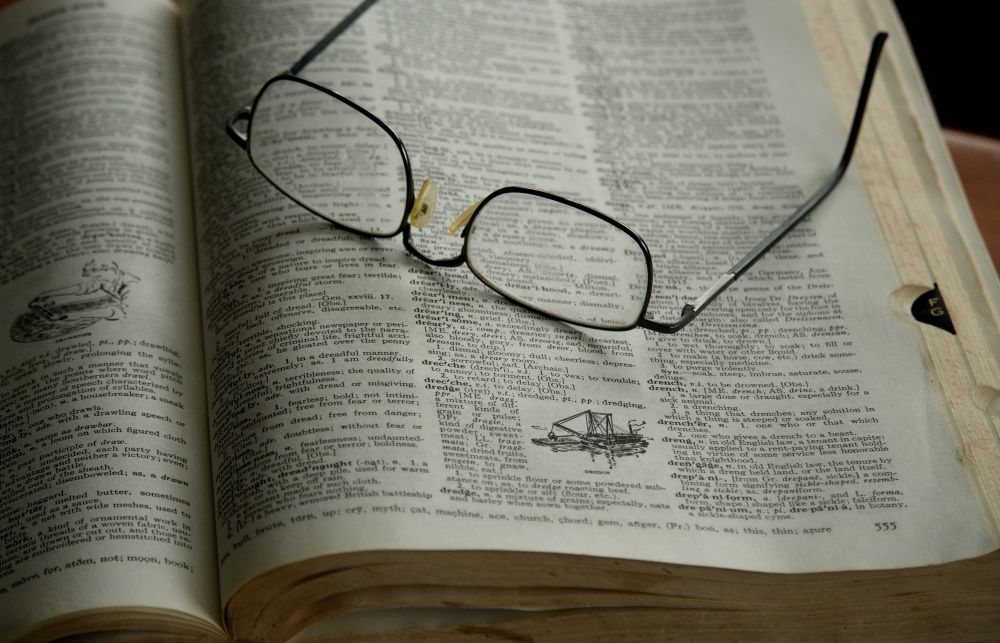 Reading glasses resting on an old dictionary post image