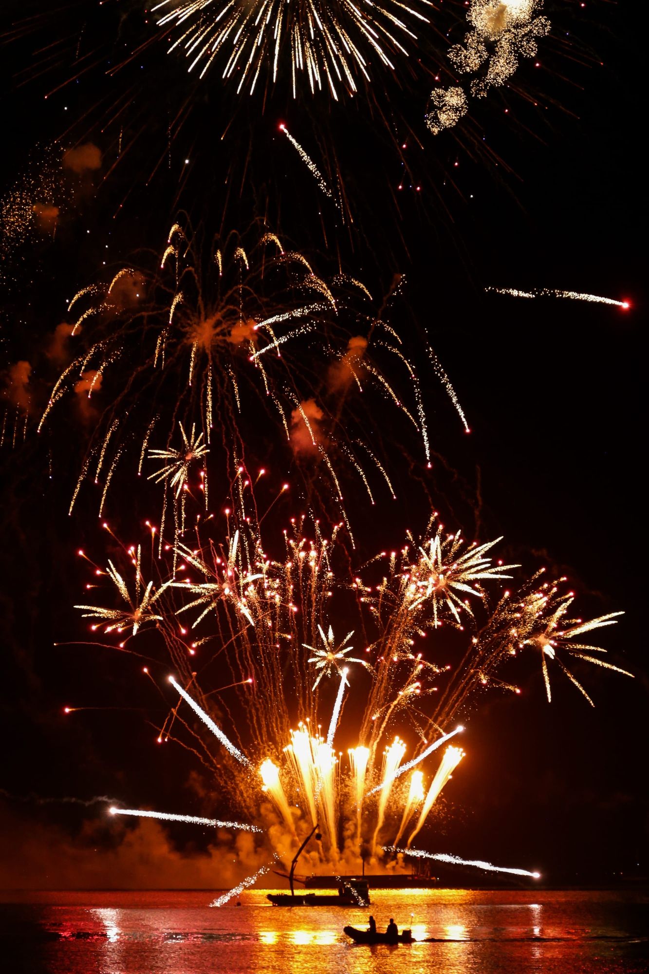 Boat silhouette on the golden sea of fireworks