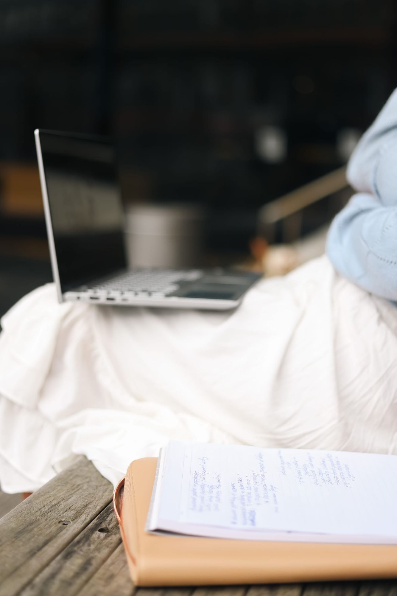 Laptop and notebook on wooden bench
