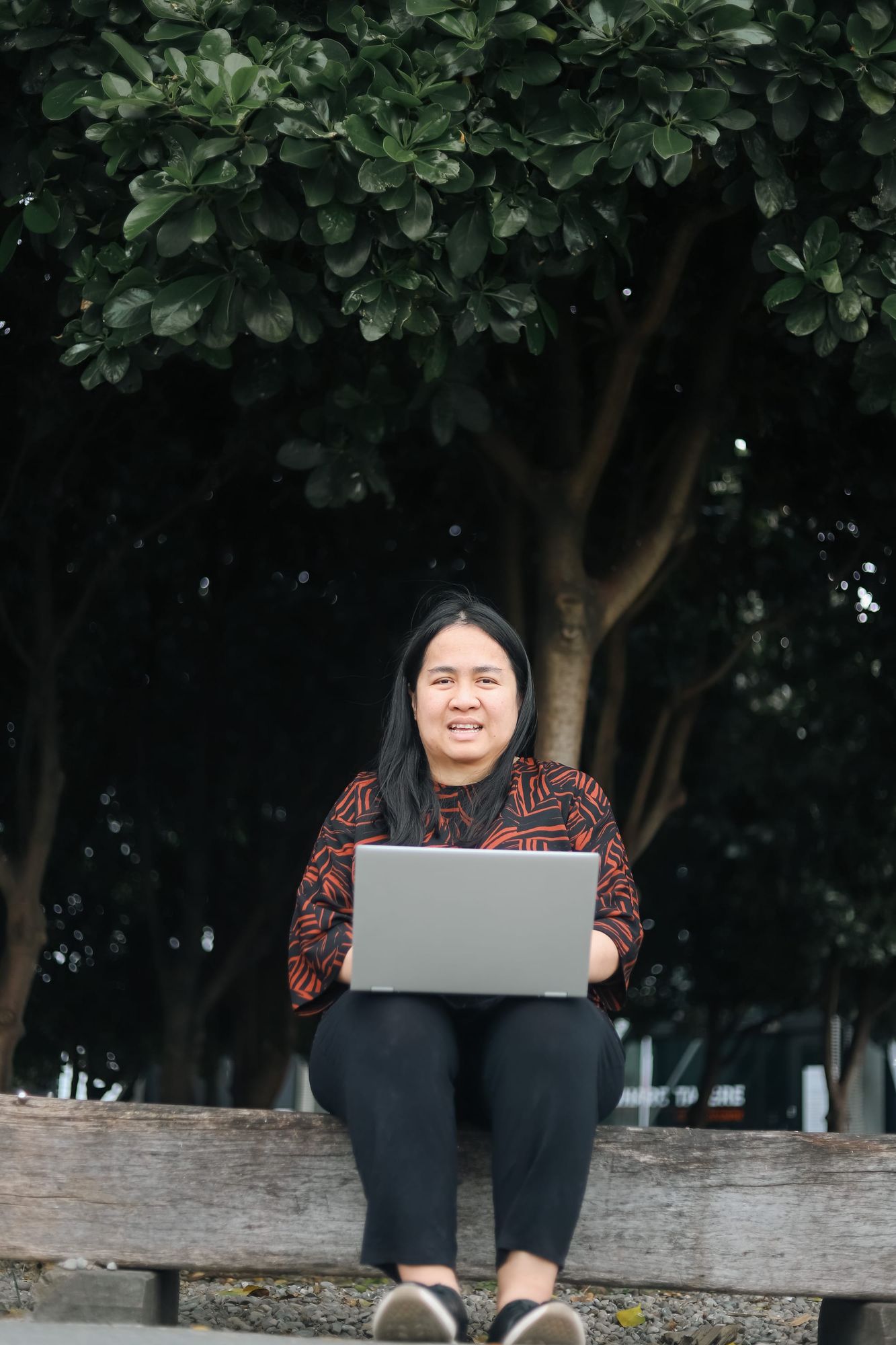 Portrait of woman smiling with laptop outdoors