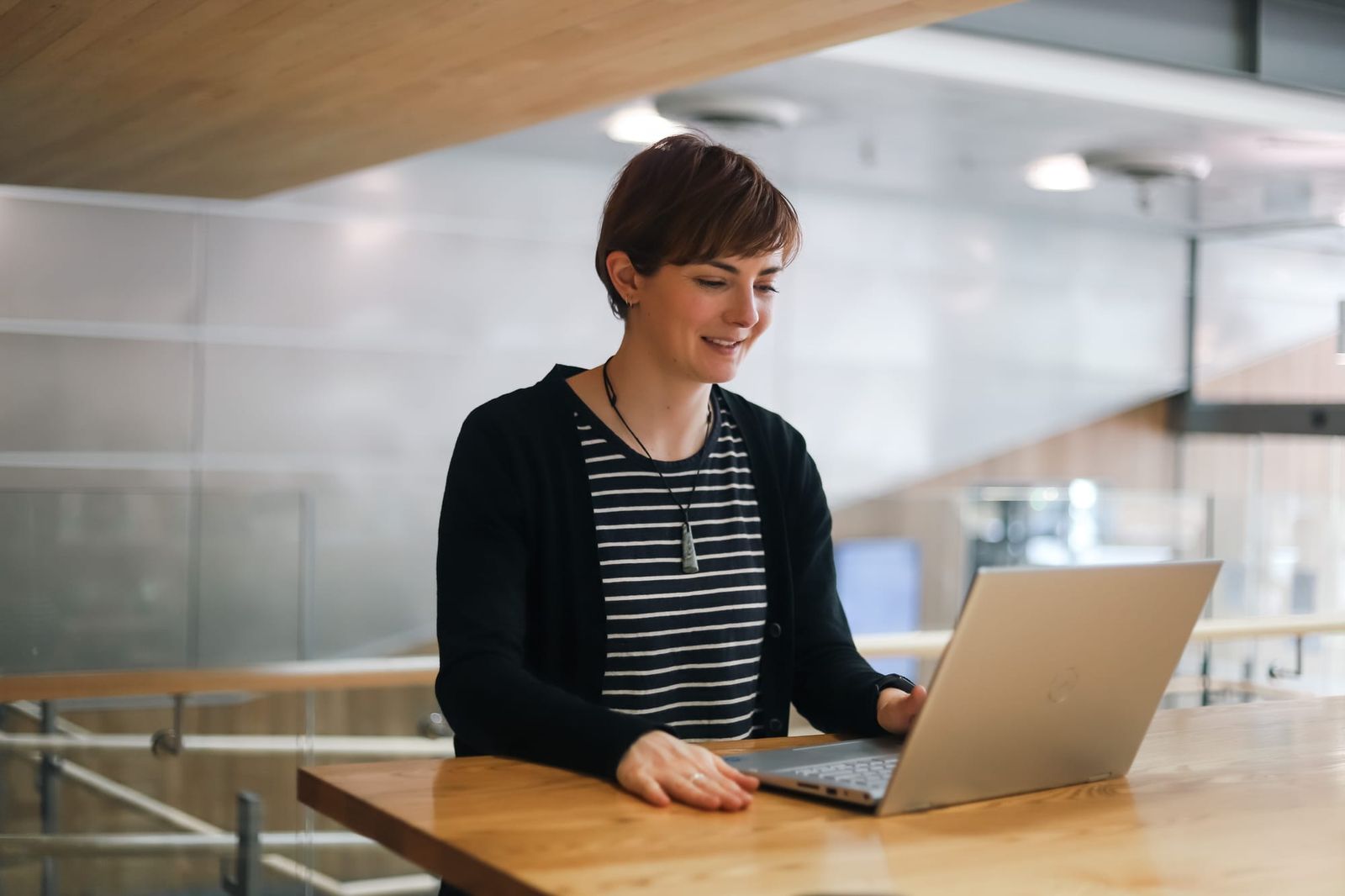 Woman smiling while working on laptop at a desk