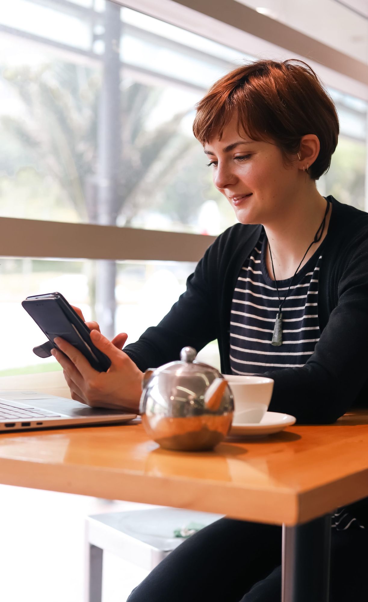 Woman smiling at phone in cafe