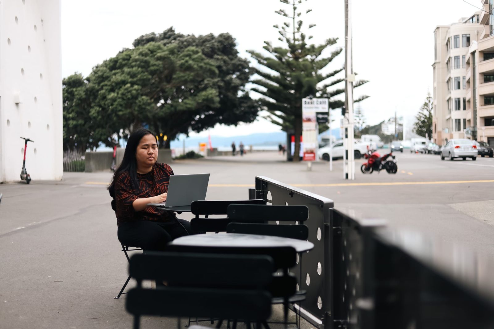 Woman working on laptop at outdoor café tables