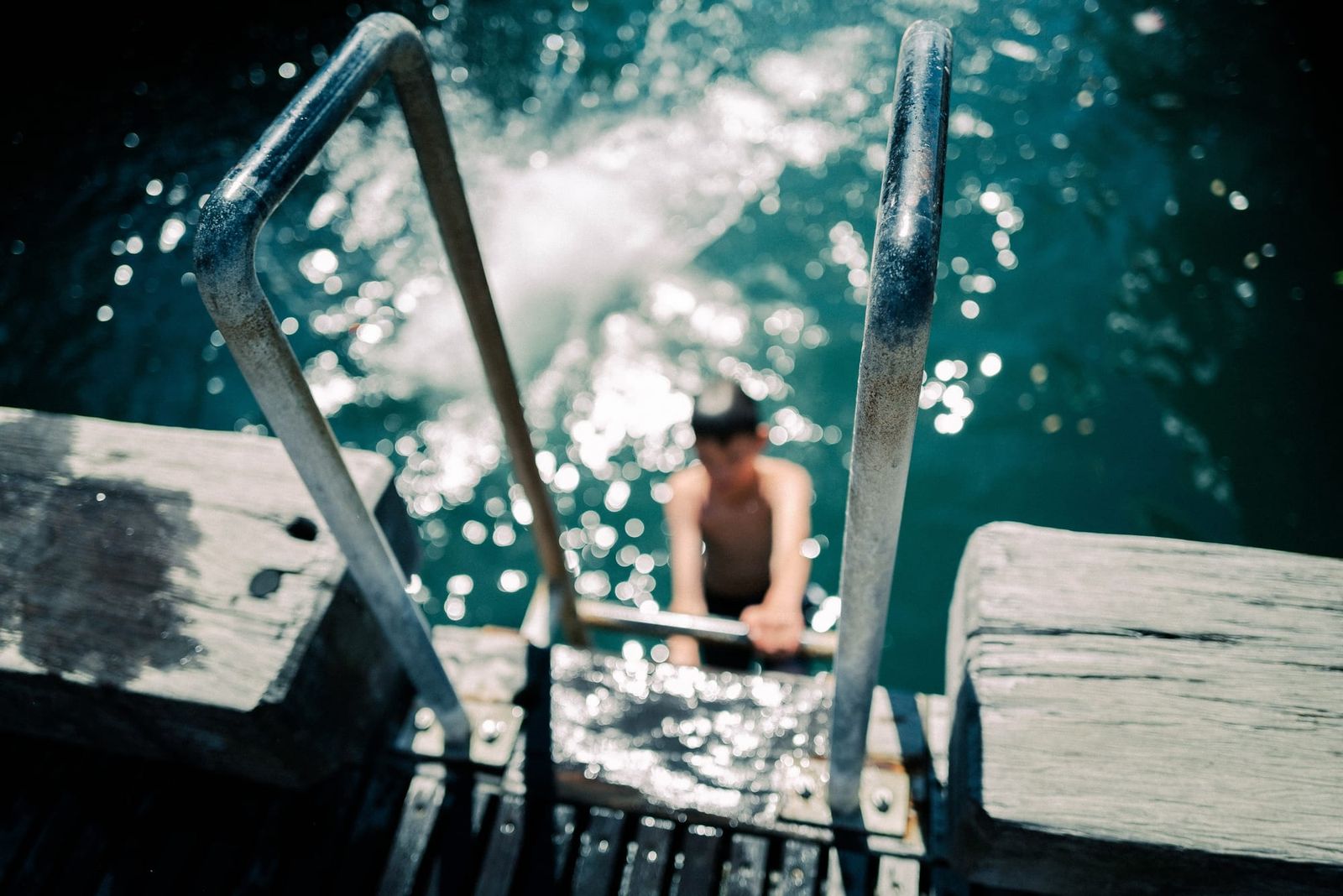 Boy climbing a ladder from sparkling water