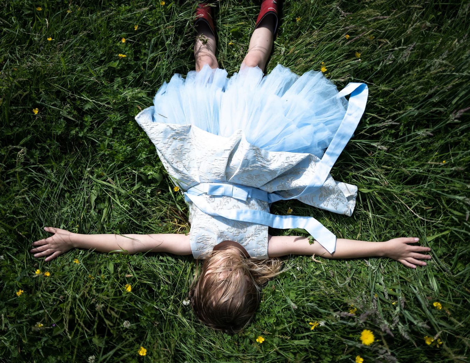 Child in a blue dress lying in the grass