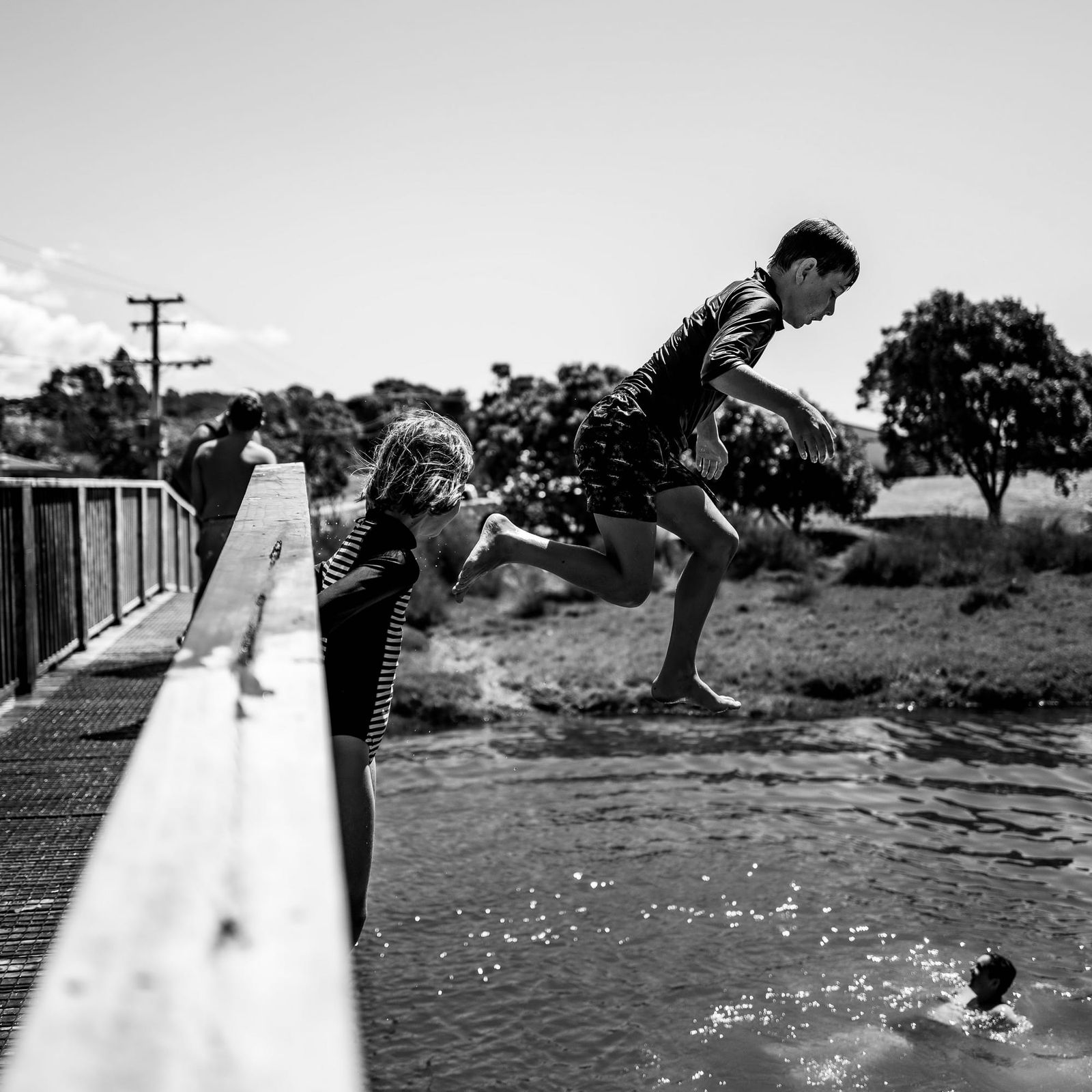 Children jumping from a bridge into the water