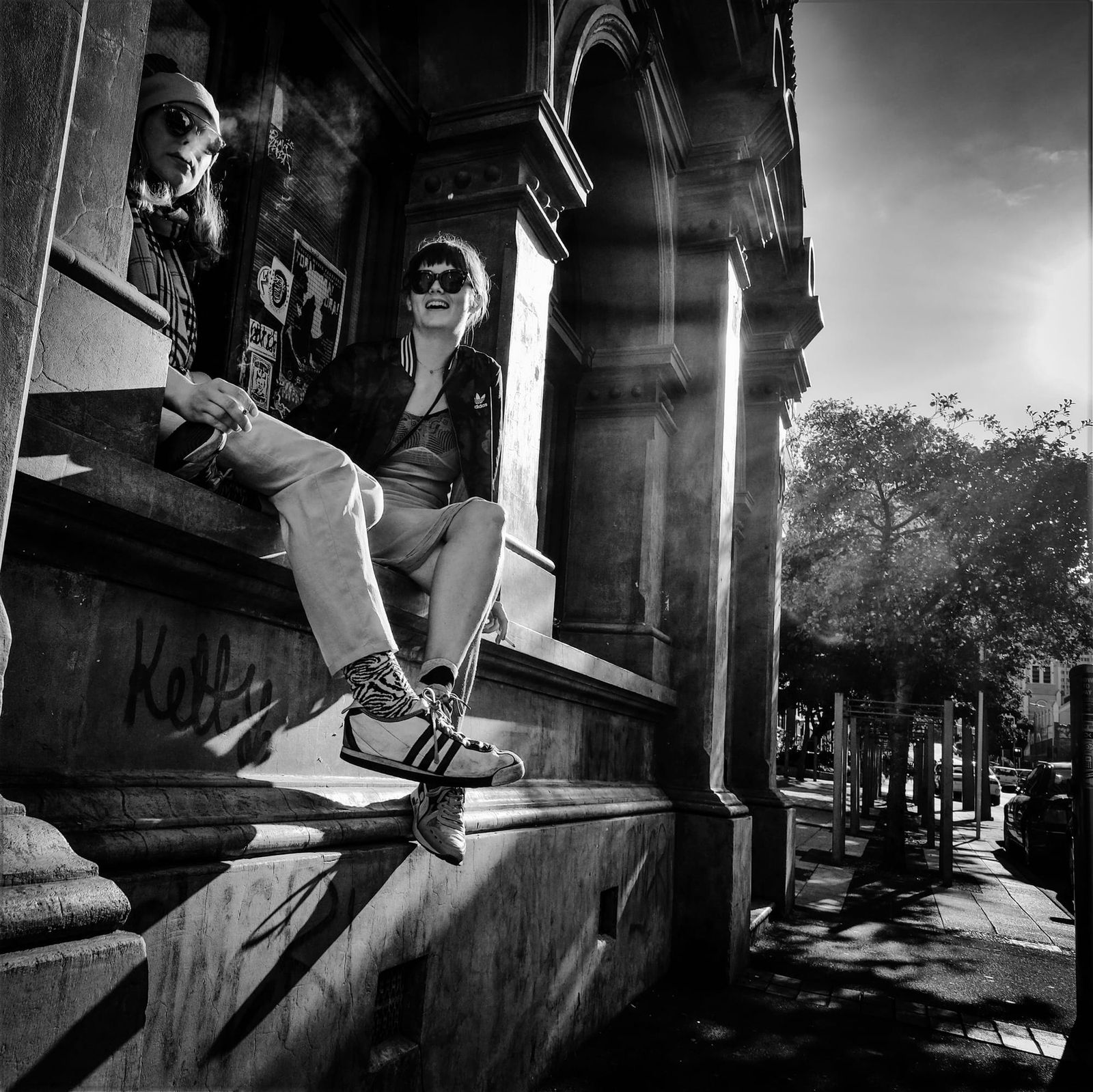 Two women sitting on a stone ledge with graffiti