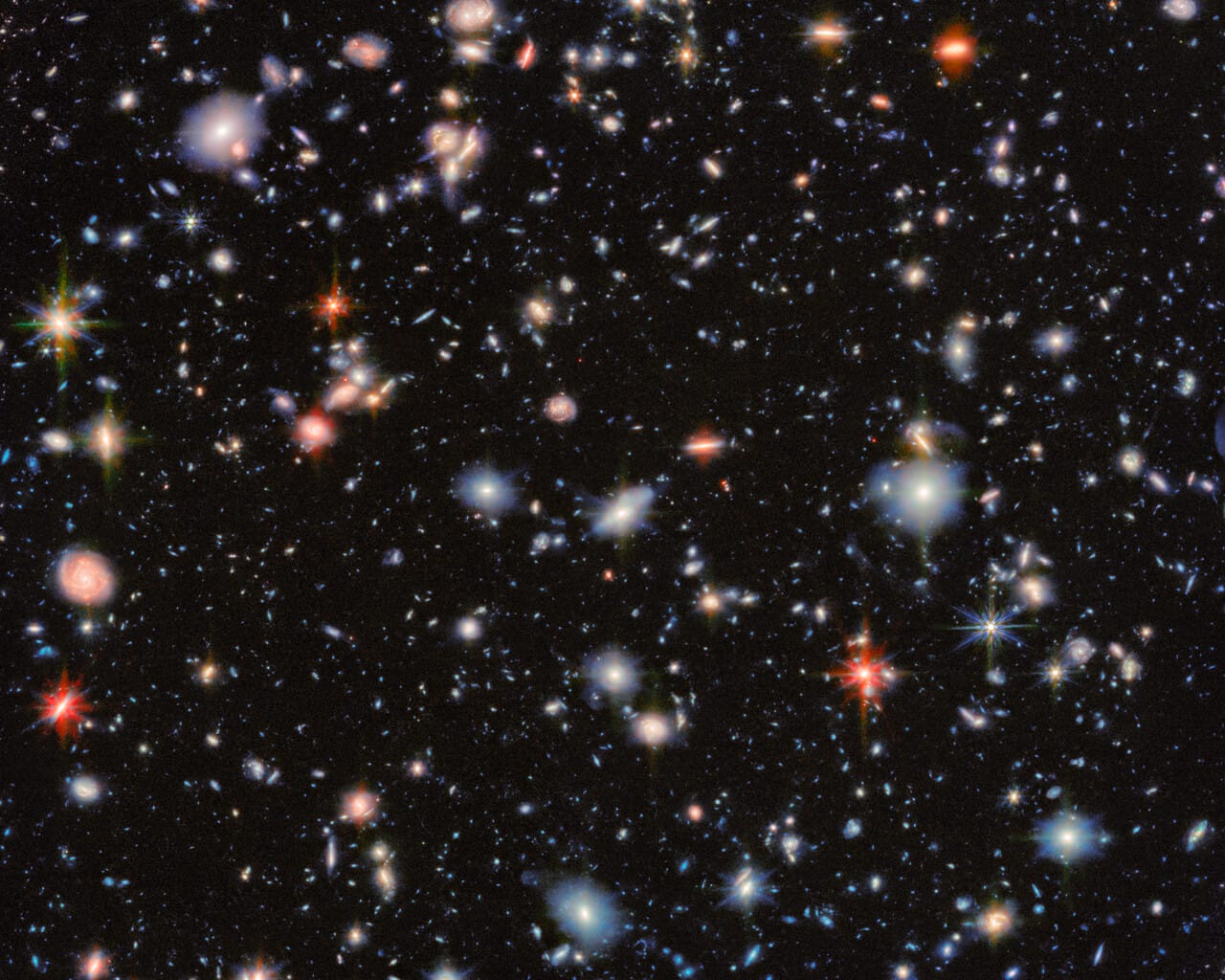 Astronomical image of the MIRI Deep Imaging Survey (MIDIS) region from the James Webb Space Telescope, showing numerous distant galaxies across a dark field.