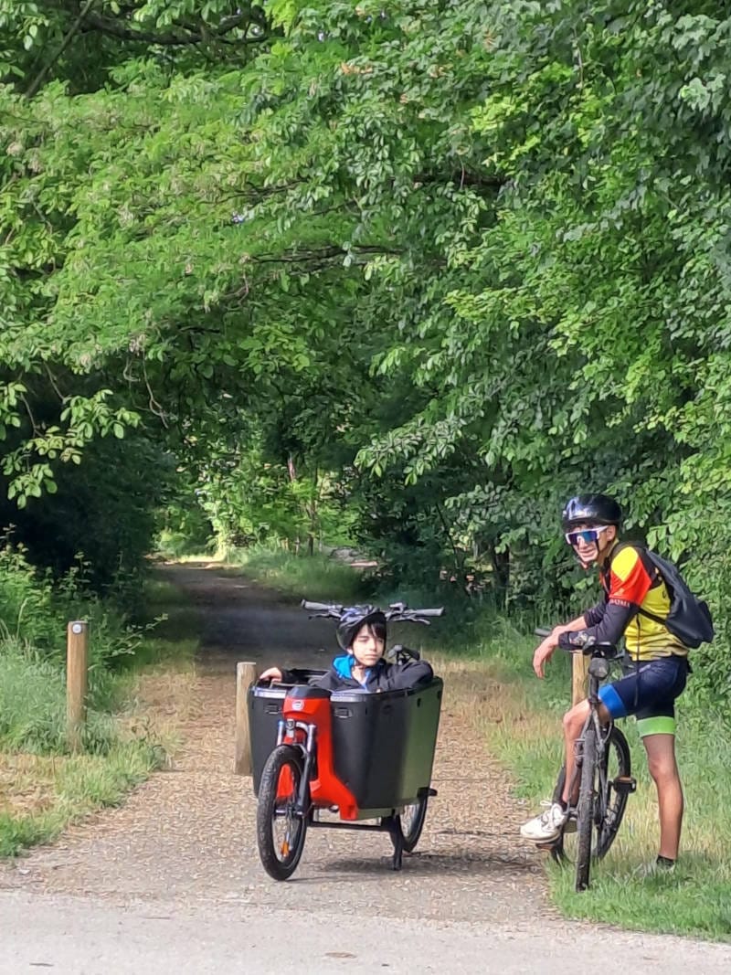 Un passager dans un vélo biporteur discute avec un cycliste