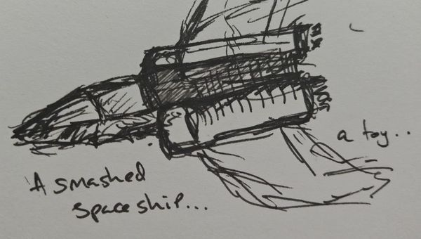 A doodle of a smashed up spaceship, sketched in pen with the words "A smashed spaceship... a toy.." written around it. 