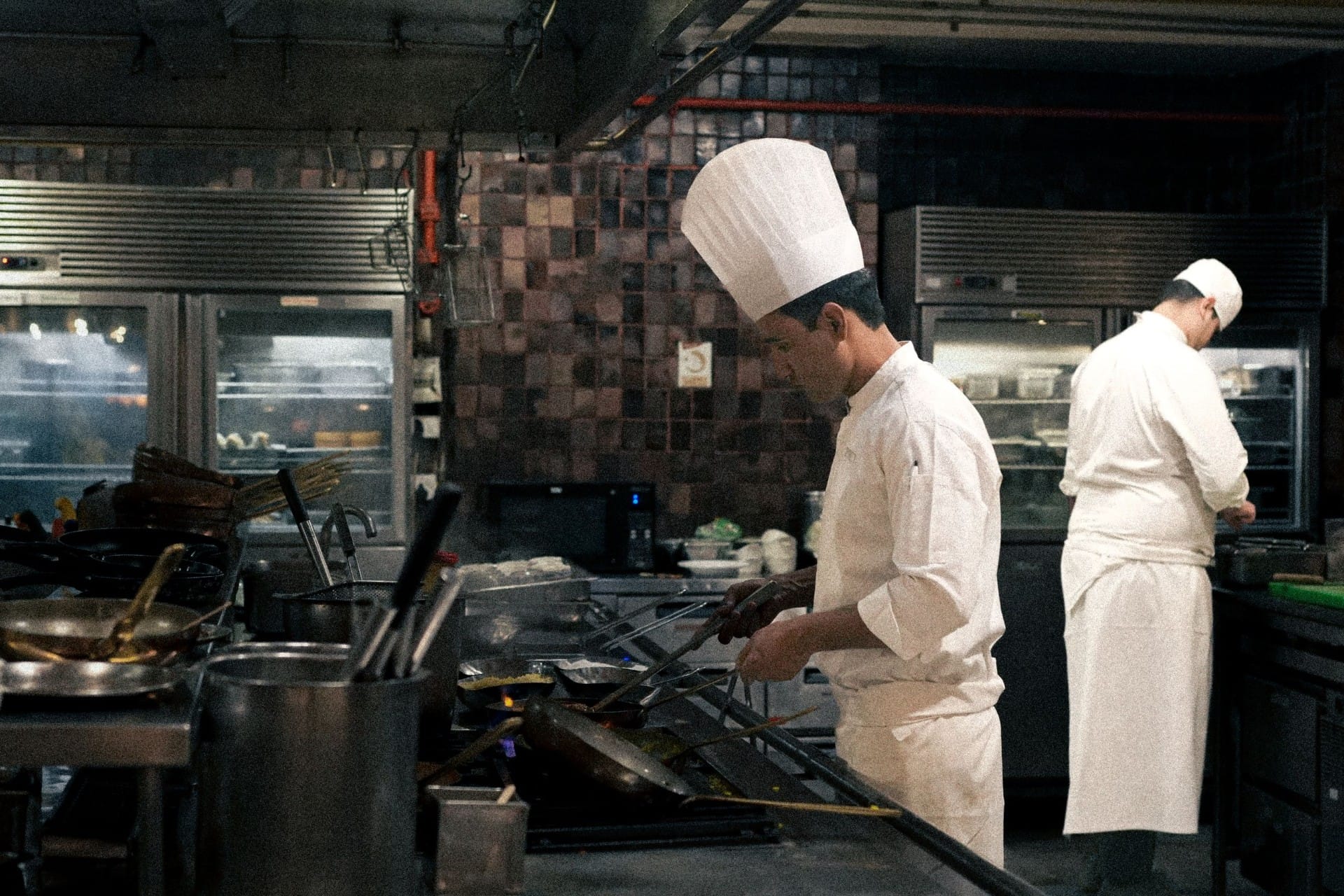 Two chefs in whites working the line in a busy commercial kitchen