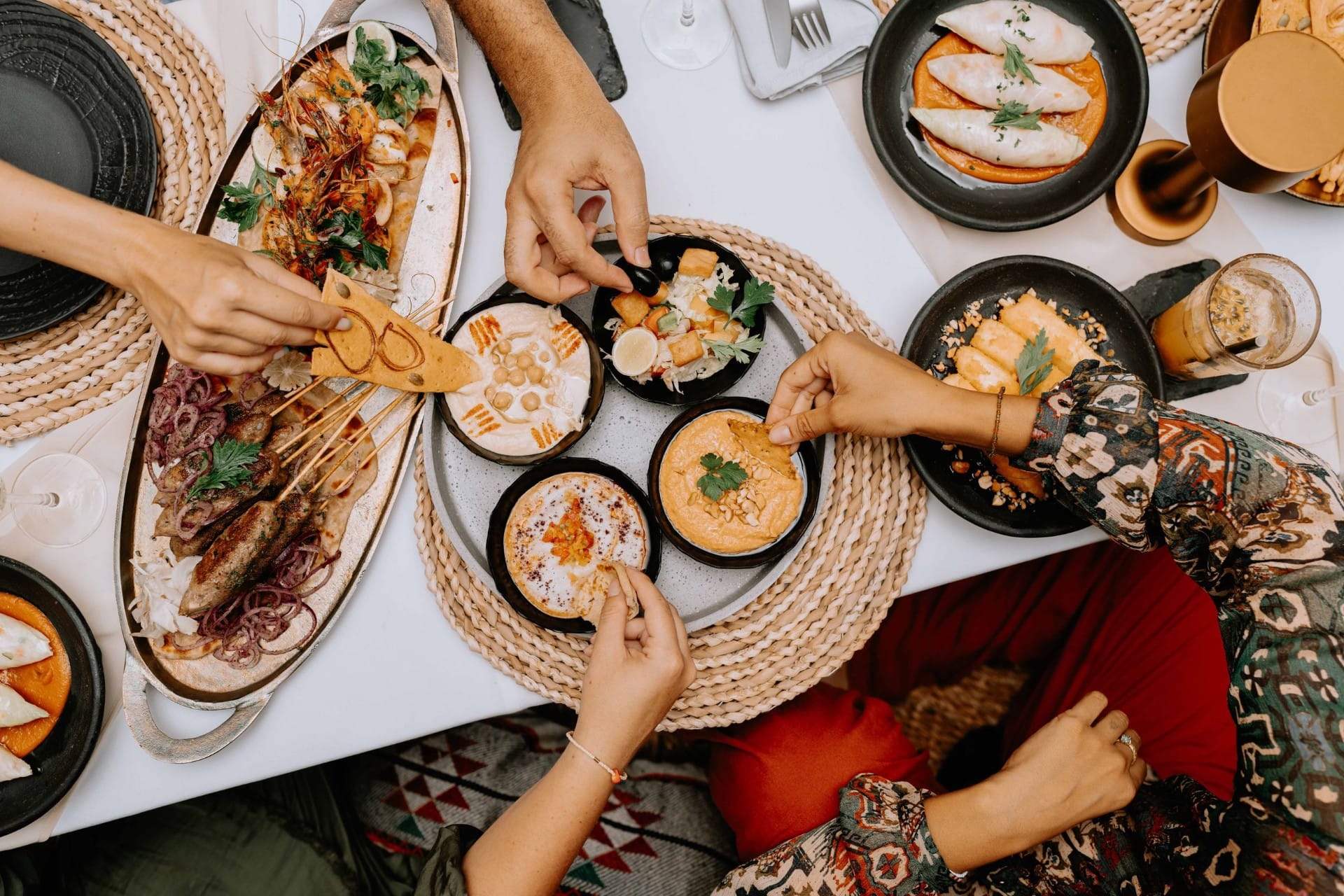 Diners sharing several small plates across a table, seen from above