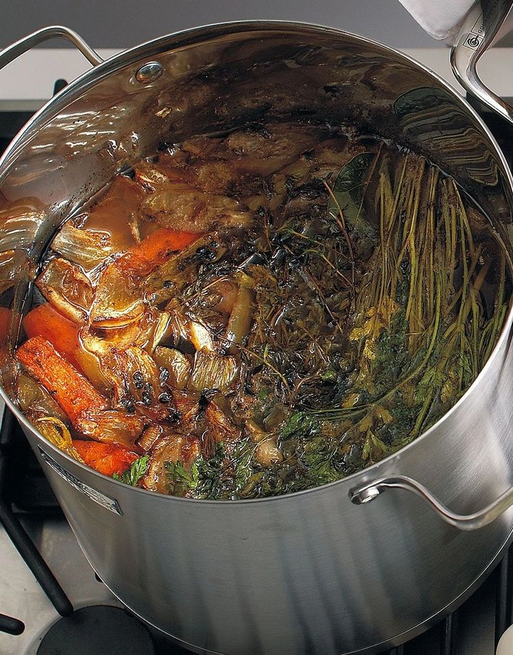 Large stockpot of beef bones, carrots and herbs simmering for stock.
