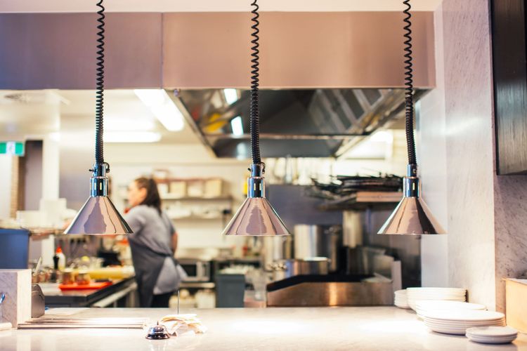 Heat lamps over the pass in a small independent kitchen during service