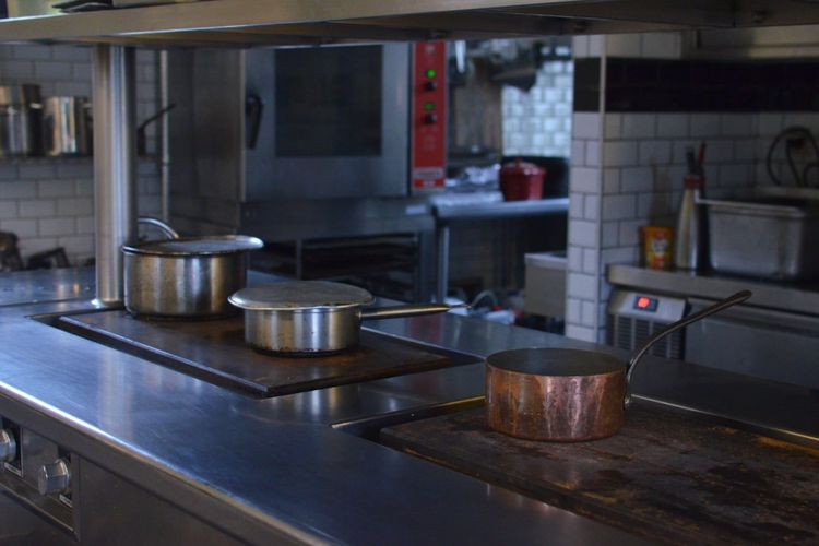 Pans sitting on the range in a stainless steel commercial kitchen