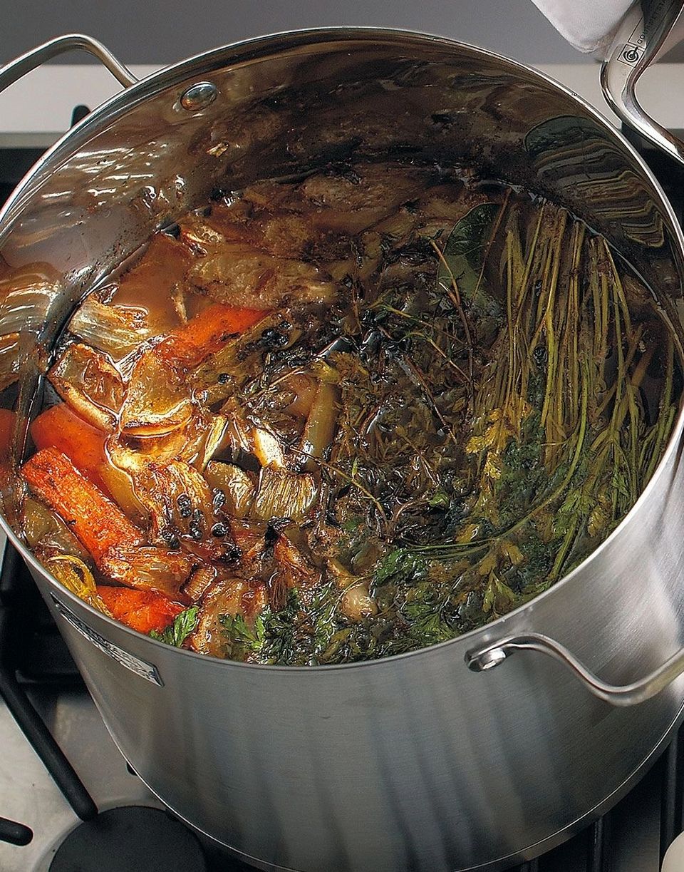 Large stockpot of beef bones, carrots and herbs simmering for stock.