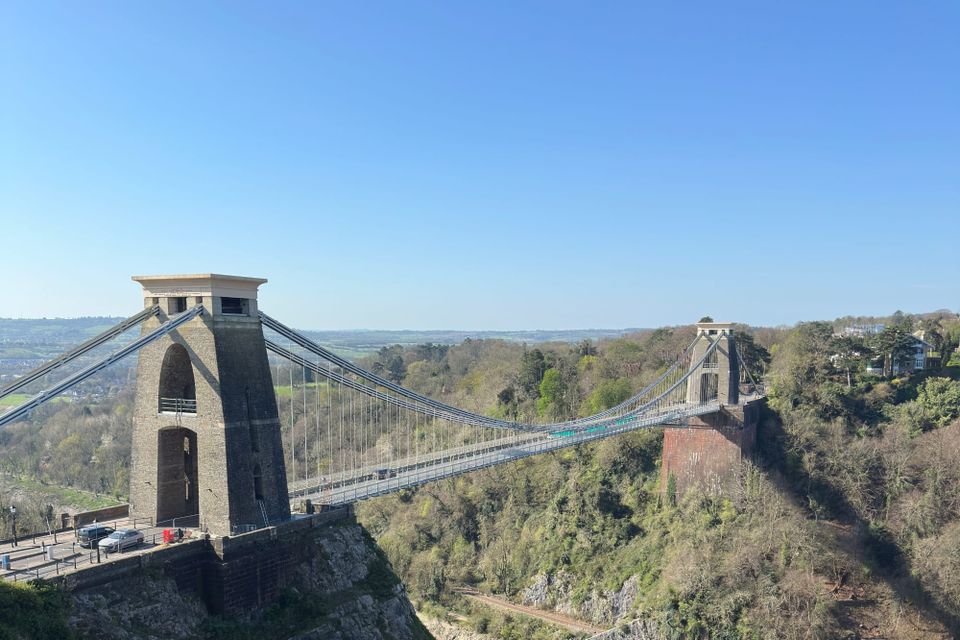 The Clifton Suspension Bridge spanning the wooded Avon Gorge, both stone towers standing above the river.