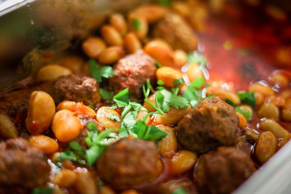 A close view of butter beans and spiced sausage in a rich tomato sauce, finished with fresh coriander
