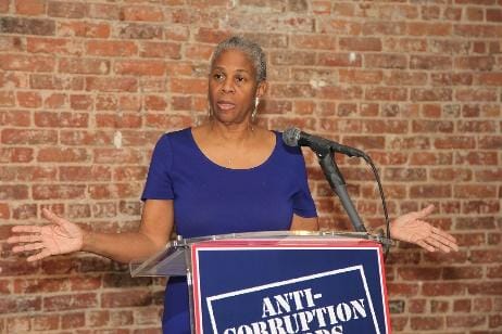 A person standing in front of a brick wallDescription automatically generated